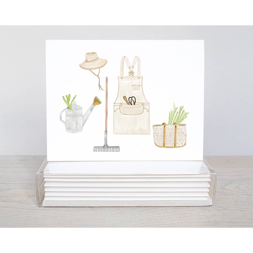 garden delight note cards feature a variety of garden supplies. A Garden apron complete with tools in the pocket, a garden bag filled with scallions, a garden rake, a weathered watering can with garlic and an adorable garden hat with leather strings. This all occasion cards will be a delight to send.